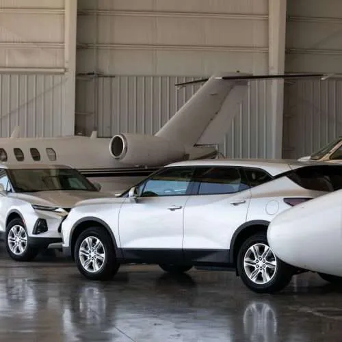Small jets and SUVs in hangar.